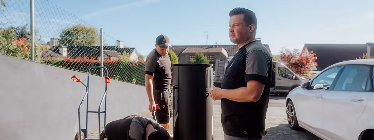 Drei Männer stehen um einen Kamin neben einem Lieferwagen herum
